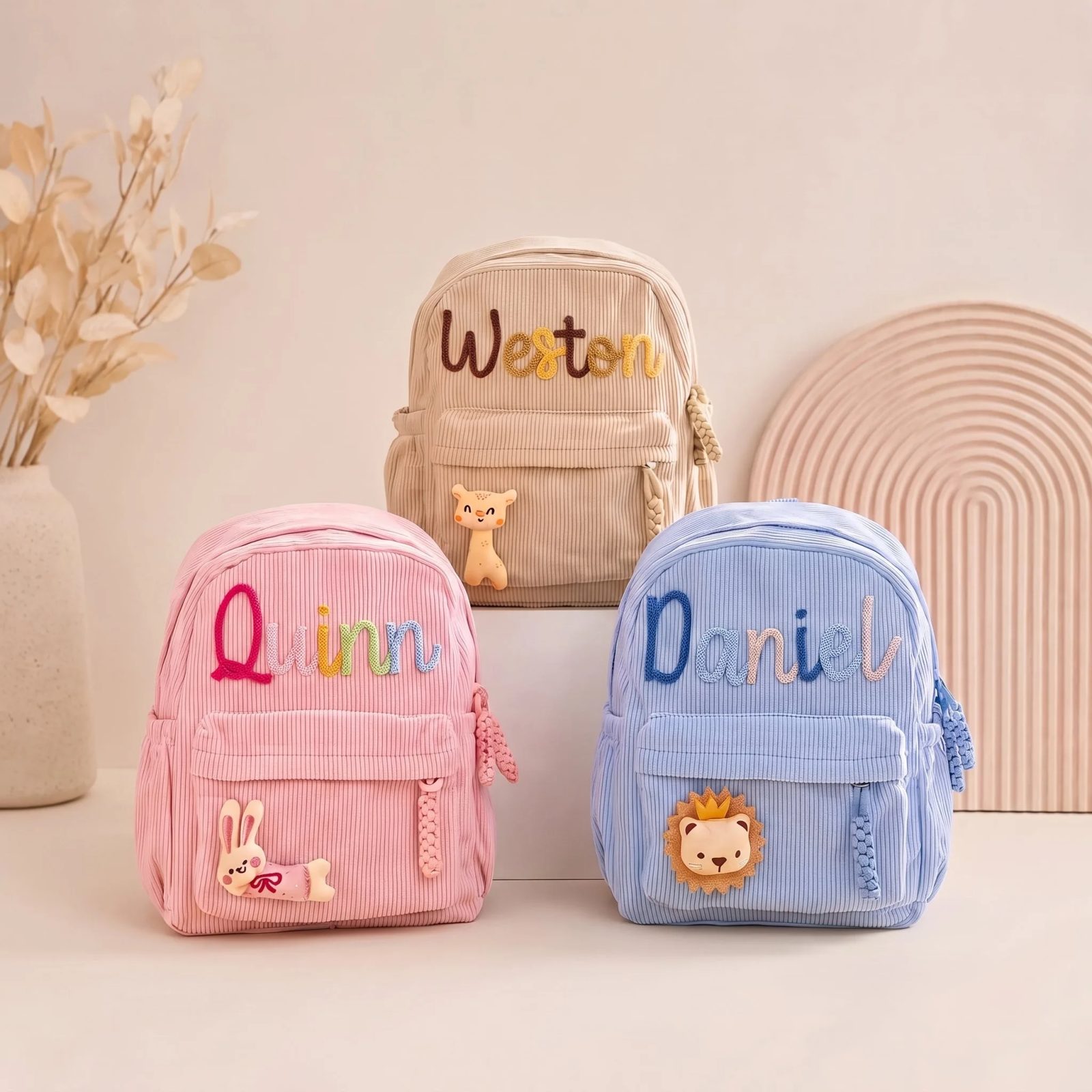 Three personalized toddler backpacks in pink beige and blue